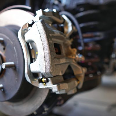 Selective focus of Brake Disc of the vehicle for repair.Automobile mechanic in process of new tire replacement.Car brake repairing in garage.Car Service and technician concept.